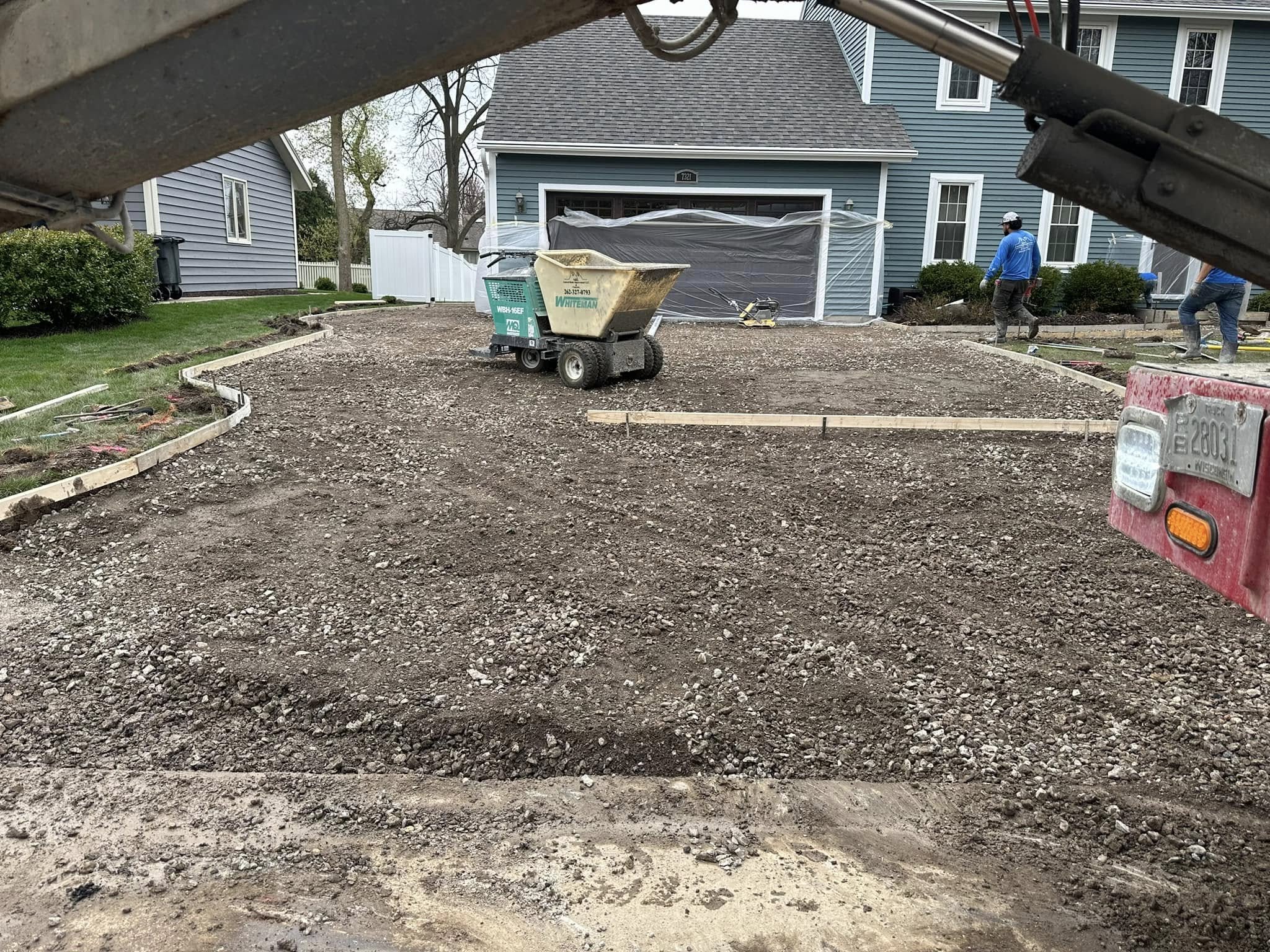 Gravel sub-base spread and leveled across driveway footprint with concrete forms set along edges